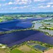 Glistening atop the water at a solar-fishery farm, blue photovoltaic panels soa…