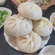 Hand‑kneaded big steamed buns with shiitake mushroom and pork filling. One is m…